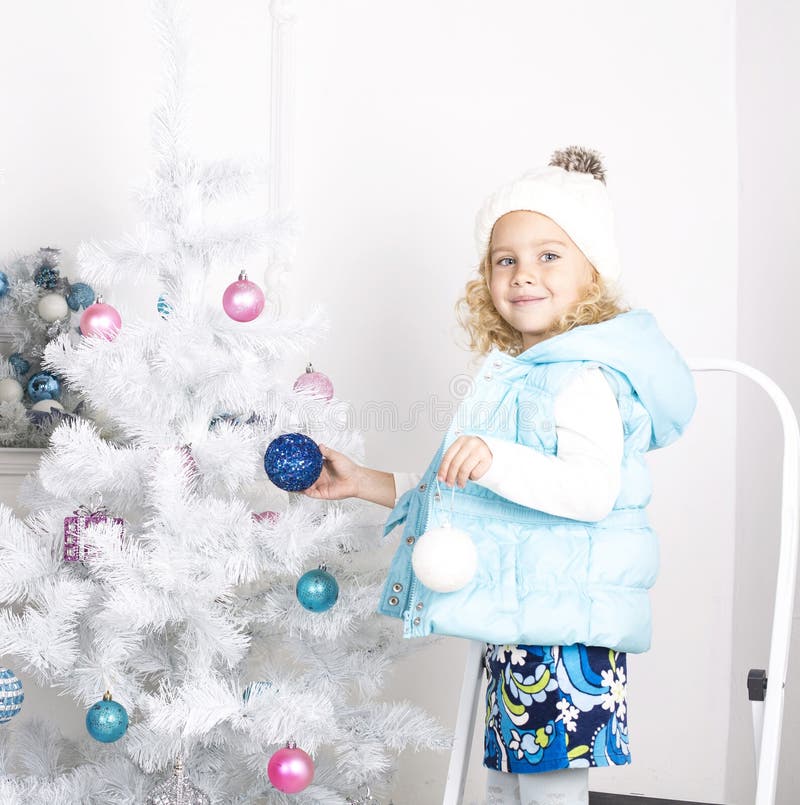 Funny little girl is decorating Christmas tree