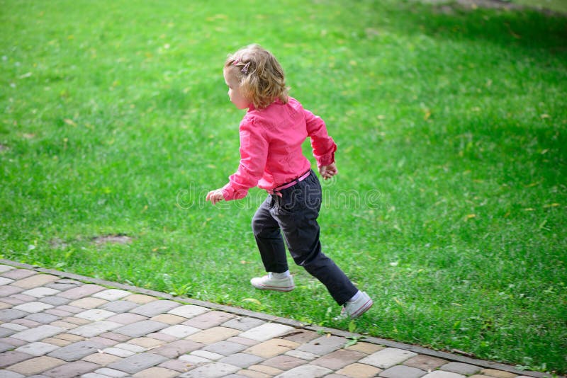 Funny little girl runing on green grass