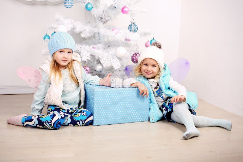 Funny little girls posing beside a decorated Christmas tree