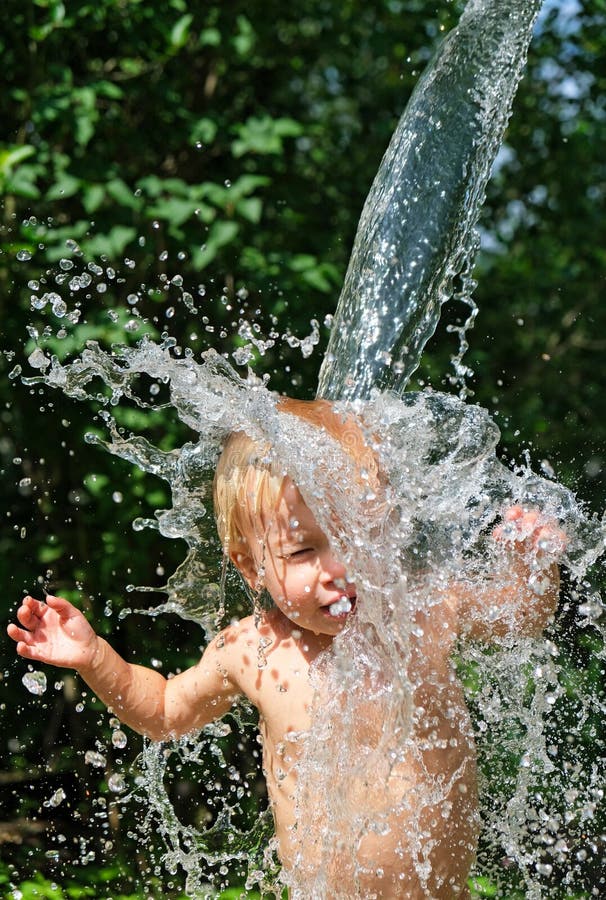 Funny little kid is poured with cold water from bucket. Water games on hot day in backyard. Hardening for health. Strengthen your