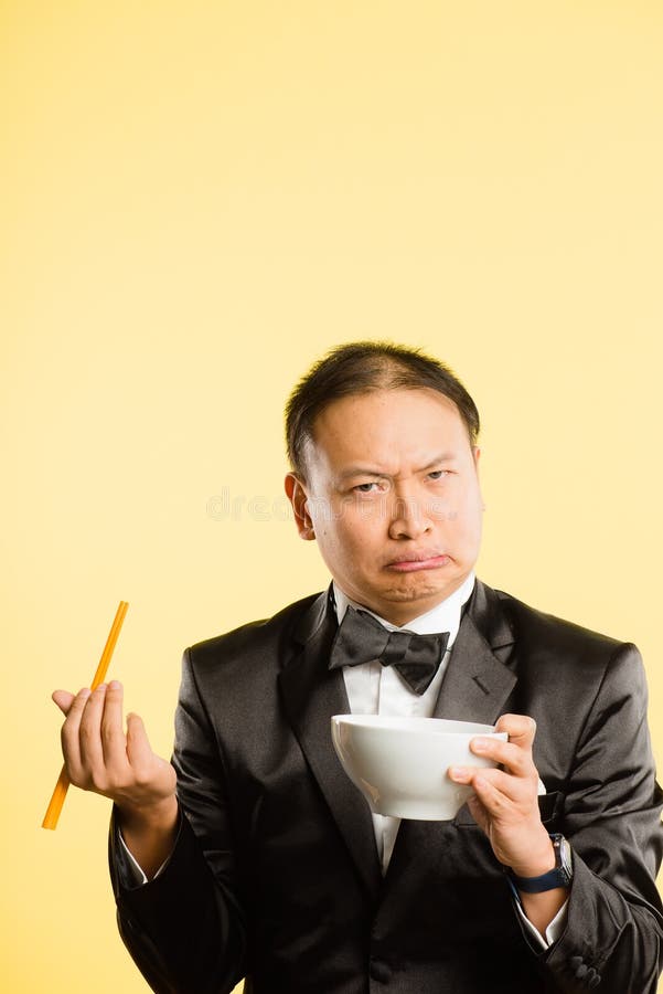 Funny looking Asian man eating and pulling faces. Funny looking Asian man eating and pulling faces