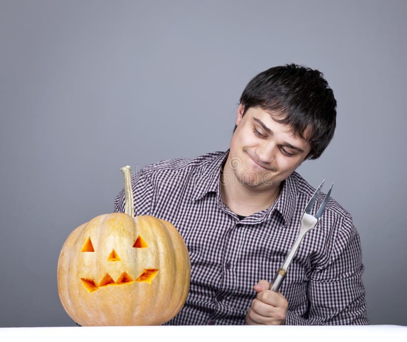 Funny men with fork try to eat a pumpkin.