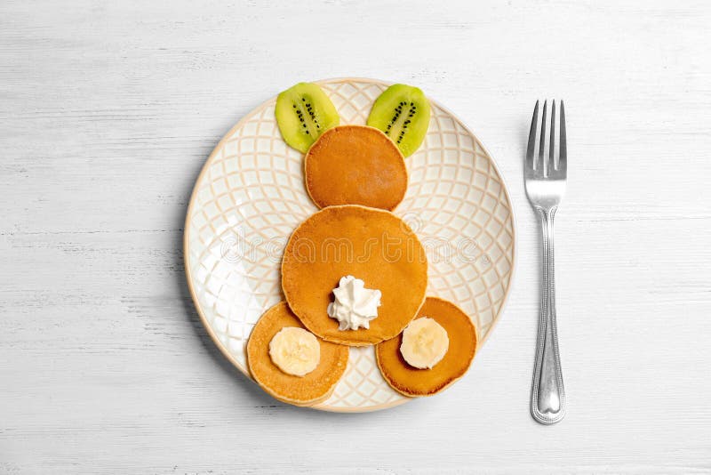 Funny pancakes for kids breakfast on wooden table, top view