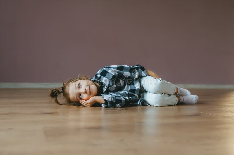 Funny portrait of lying cute little girl on a floor indoors