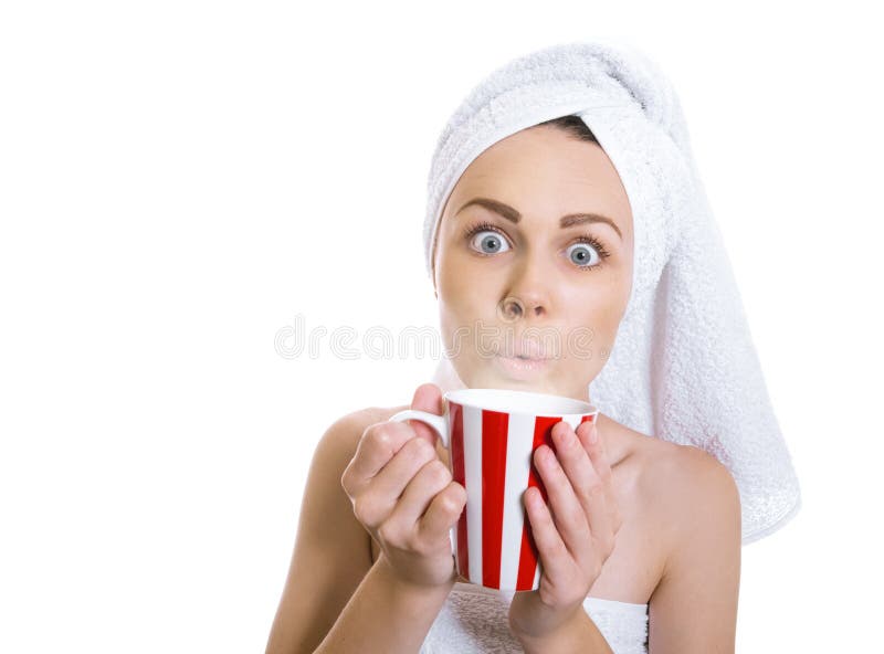 Funny woman wrapped in a towel drinking hot tea or coffee. Young girl holding cup - mug of dring, isolated on white