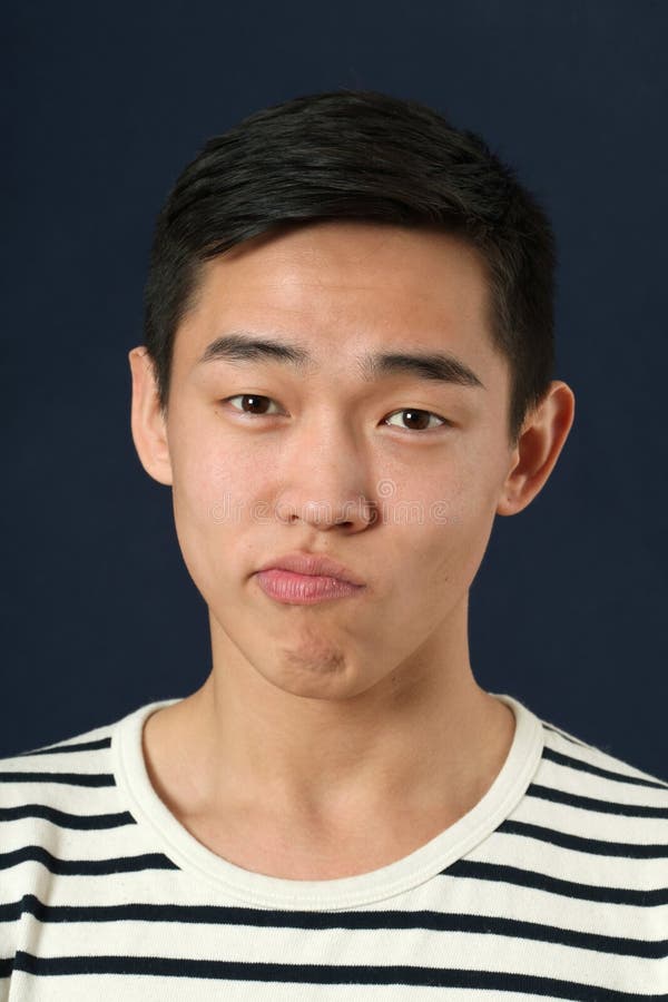 Funny young Asian man making face and looking at camera