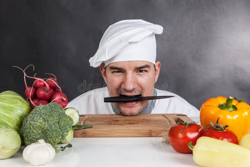 Funny young chef with knife and vegetable