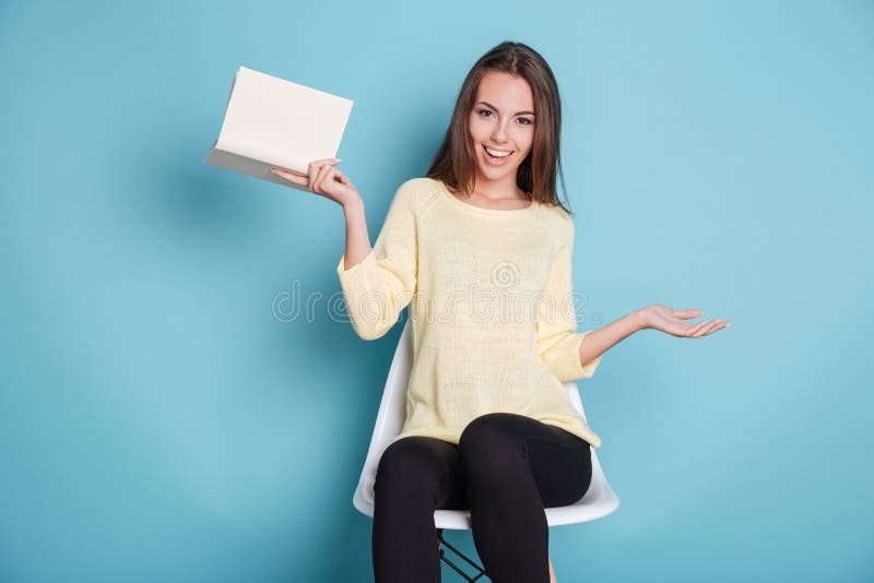 Funny young girl with a book over blue background royalty free stock photography Funny young girl with a book over blue background royalty free stock photography