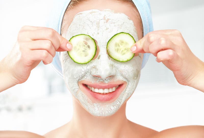 Funny young girl with a mask for skin face and cucumbers royalty free stock photography Funny young girl with a mask for skin face and cucumbers royalty free stock photography