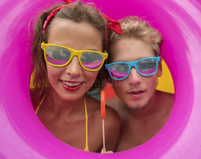 Funny young happy beach couple smiling in the middle of pink inflatable ring. stock images Funny young happy beach couple smiling in the middle of pink inflatable ring. stock images