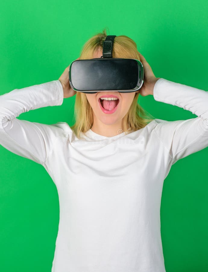 Funny young woman with VR. Woman wearing virtual reality goggles in green background. Amazed young woman touching the stock photography Funny young woman with VR. Woman wearing virtual reality goggles in green background. Amazed young woman touching the stock photography