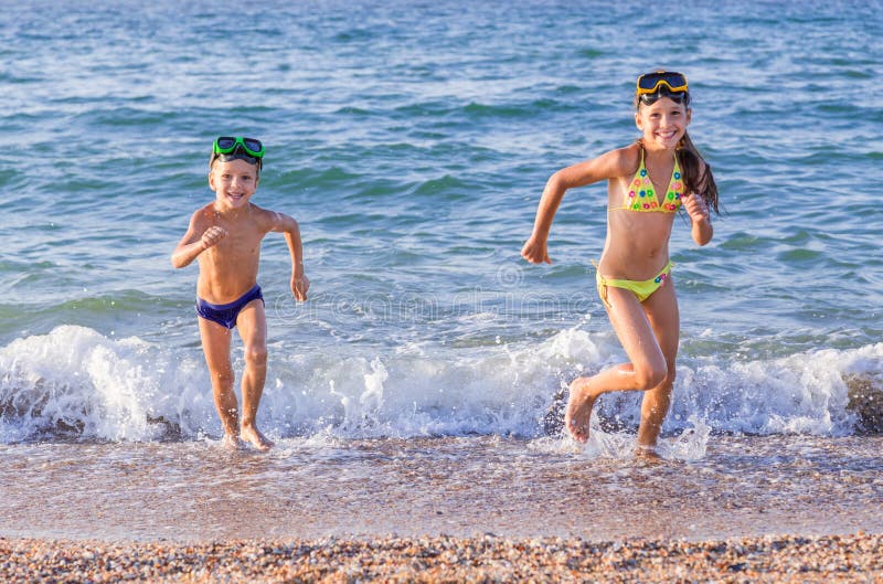 Funzionamenti felici dei bambini dal mare fotografia stock libera da diritti Funzionamenti felici dei bambini dal mare fotografia stock libera da diritti