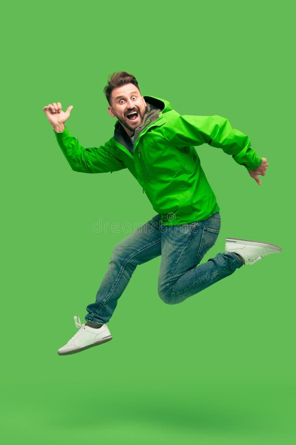 Funzionamento barbuto bello del giovane isolato su verde fotografie stock Funzionamento barbuto bello del giovane isolato su verde fotografie stock