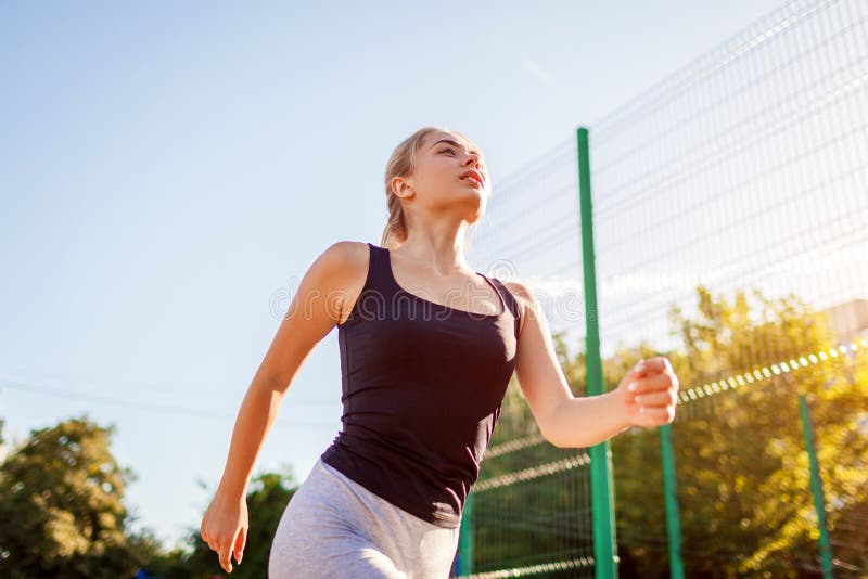 Funzionamento dell'atleta della giovane donna sullo sportsground di estate Modo di vivere sano immagini stock libere da diritti Funzionamento dell'atleta della giovane donna sullo sportsground di estate Modo di vivere sano immagini stock libere da diritti