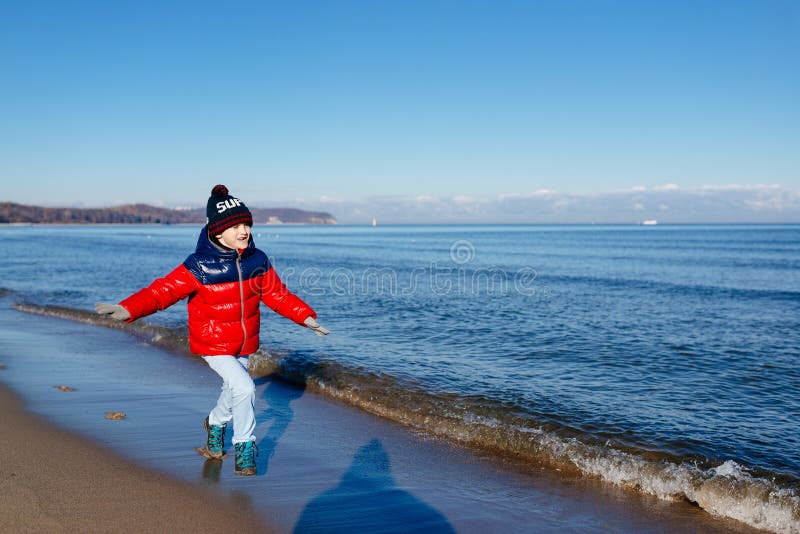 Funzionamento felice del ragazzo del piccolo bambino sulla spiaggia fotografia stock Funzionamento felice del ragazzo del piccolo bambino sulla spiaggia fotografia stock