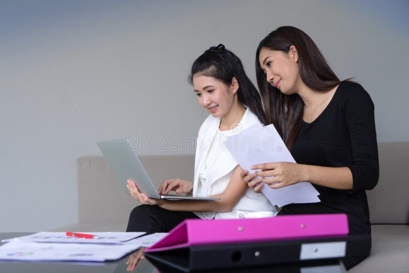 Funzionamento felice di due un giovane donne di affari insieme al computer portatile in ufficio fotografie stock libere da diritti Funzionamento felice di due un giovane donne di affari insieme al computer portatile in ufficio fotografie stock libere da diritti