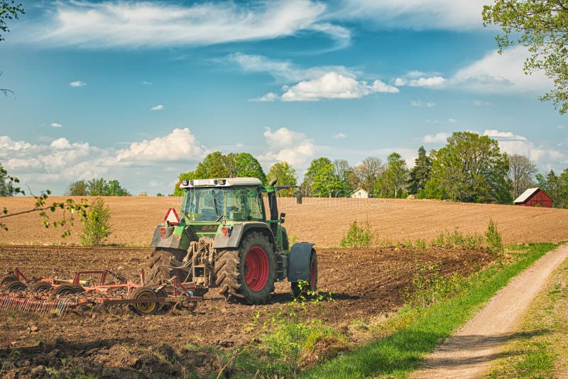 Funzionamento sull'azienda agricola, un trasporto agricolo moderno, un agricoltore del trattore che lavora nel campo, terra ferti