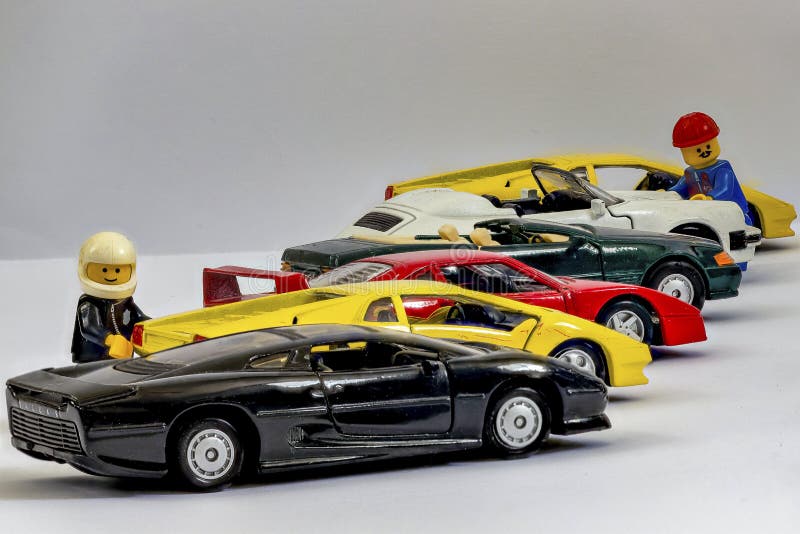 Fuoco-impilando con le figure di Lego accanto ad una fila delle automobili del giocattolo interamente a fuoco