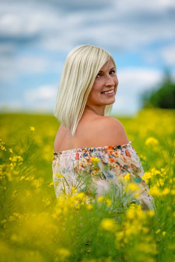Fuoco molle e selettivo Bella, donna attraente e bionda in un prato giallo del fiore immagine stock libera da diritti Fuoco molle e selettivo Bella, donna attraente e bionda in un prato giallo del fiore immagine stock libera da diritti
