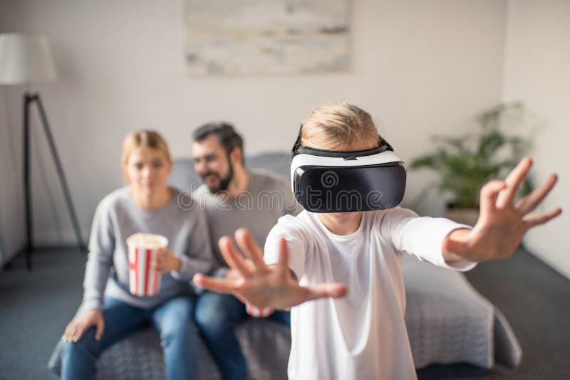 fuoco selettivo dei genitori con popcorn che esamina bambino che gioca in cuffia avricolare del vr fotografia stock libera da diritti fuoco selettivo dei genitori con popcorn che esamina bambino che gioca in cuffia avricolare del vr fotografia stock libera da diritti
