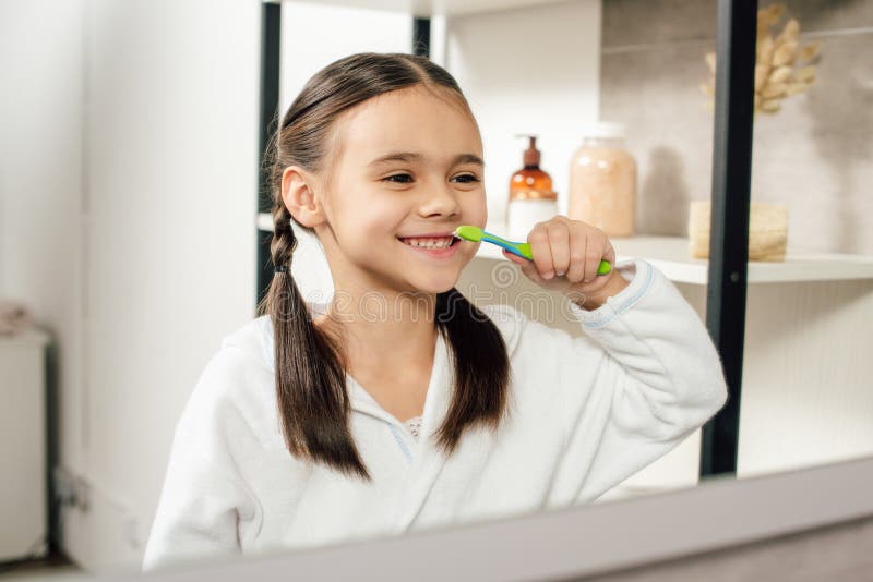 fuoco selettivo del bambino in accappatoio bianco che guardano per rispecchiarsi e denti di spazzolatura fotografia stock libera da diritti fuoco selettivo del bambino in accappatoio bianco che guardano per rispecchiarsi e denti di spazzolatura fotografia stock libera da diritti