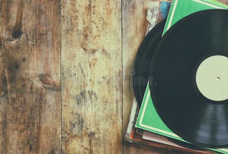 Selective focus of records stack with record on top over wooden table. vintage filtered. Selective focus of records stack with record on top over wooden table. vintage filtered.