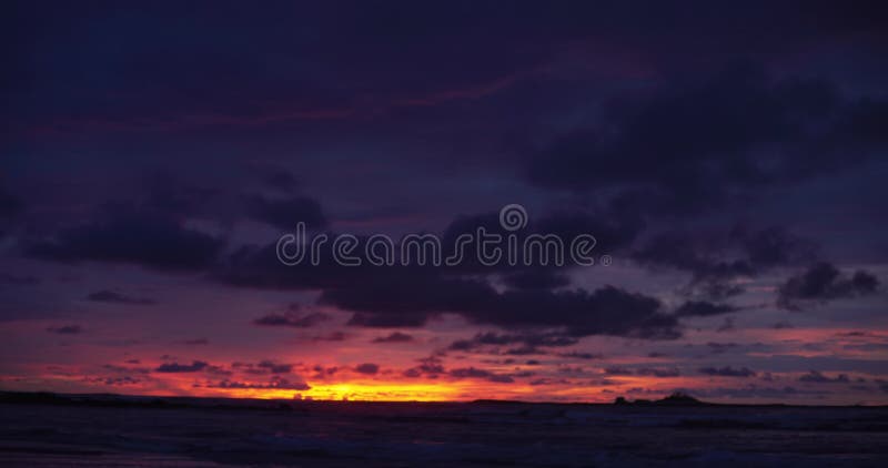 Fuori dalla piastra di sfondo focalizzata del bellissimo tramonto viola e arancione sulla spiaggia