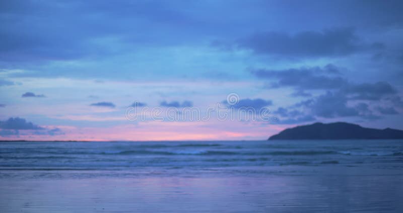 Fuori dalla piastra di sfondo focalizzata di un bellissimo tramonto viola e blu sulla spiaggia