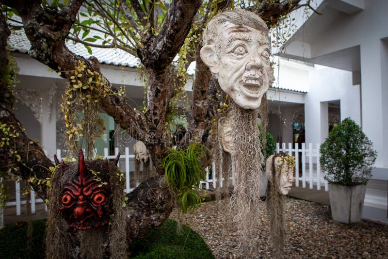Furchtsame Masken, die an den B?umen bei Wat Rong Khun h?ngen - der wei?e Tempel - an einem bew?lkten Tag Chiang Rai stockbilder Furchtsame Masken, die an den B?umen bei Wat Rong Khun h?ngen - der wei?e Tempel - an einem bew?lkten Tag Chiang Rai stockbilder