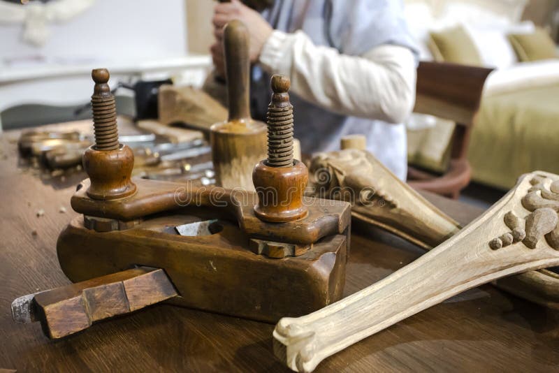 Furniture manufacturing with joiner tools, wooden decorative elements and carpenter, working with chisel at the background. royalty free stock photo Furniture manufacturing with joiner tools, wooden decorative elements and carpenter, working with chisel at the background. royalty free stock photo