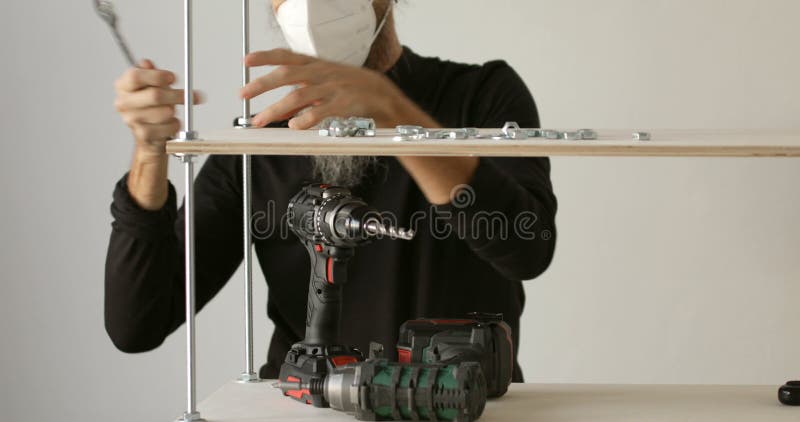 Furniture worker assembling plywood iron shelf