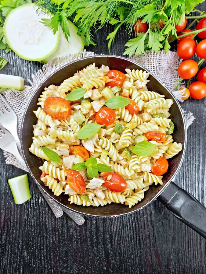 Fusilli with chicken and tomatoes in pan on black board top