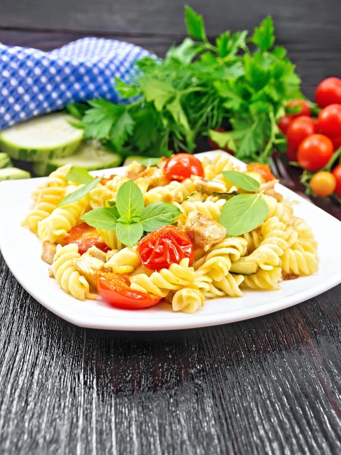 Fusilli with chicken and tomatoes in plate on wooden board