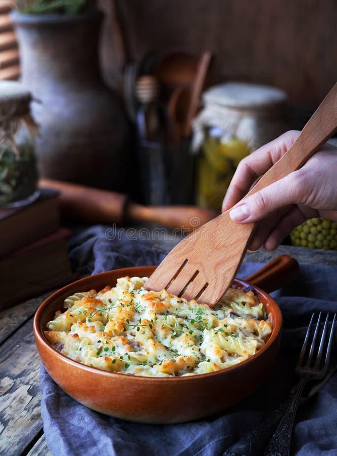 Fusilli pasta casserole with chicken, cheese dor blu and spices served on a clay plate on a wooden kitchen table in