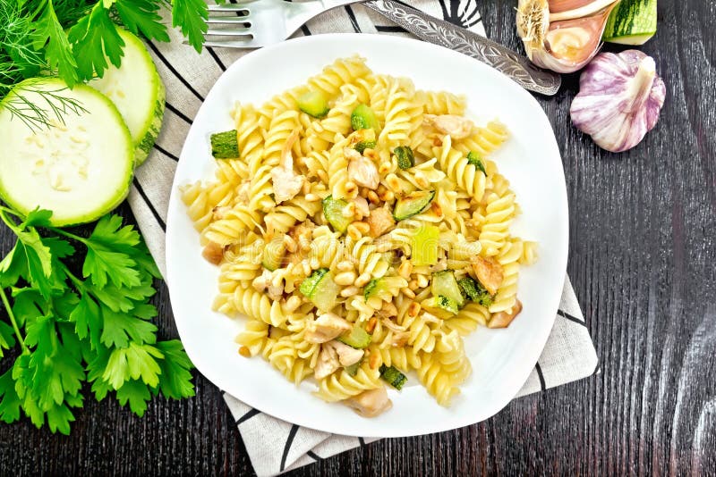 Fusilli with chicken and zucchini in plate on wooden board top