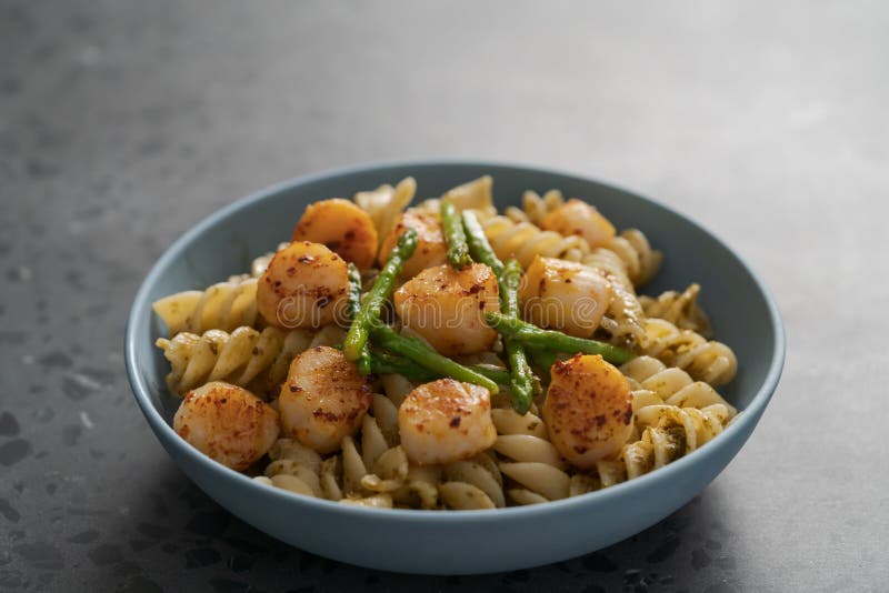 Fusilli Pasta with Scallops and Asparagus in Blue Bowl on Concrete