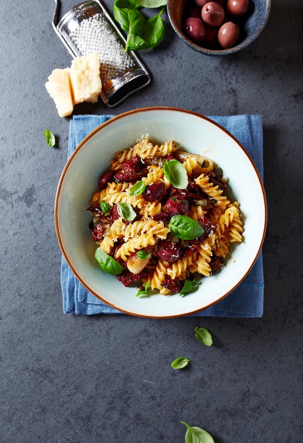 Fussili pasta med oliv, schalottenlökar, torkade tomater och parmesan royaltyfri bild Fussili pasta med oliv, schalottenlökar, torkade tomater och parmesan royaltyfri bild