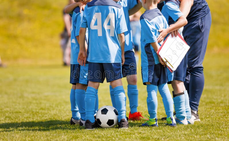 Futbolistas en un círculo apiñados con un entrenador durante el descanso. Placa blanca de tácticas de retención de entrenadores foto de archivo libre de regalías