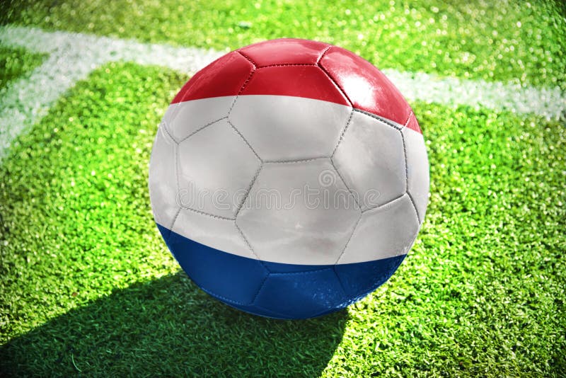 Futbolowa piłka z flaga państowowa holandie kłama na zielenieje pole zdjęcia royalty free Futbolowa piłka z flaga państowowa holandie kłama na zielenieje pole zdjęcia royalty free
