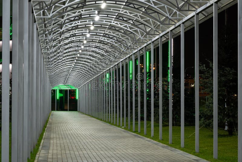 Futuristic pedestrian overpass tunnel with bright lighting, receding into the distance at night. Urban geometry