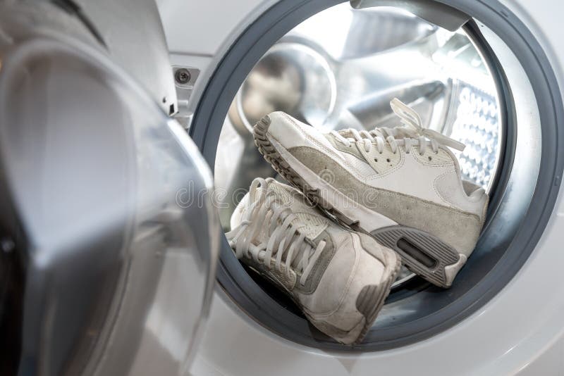 Fußbekleidungshygiene- Paar weiße Turnschuhe in der Waschmaschine stockbild