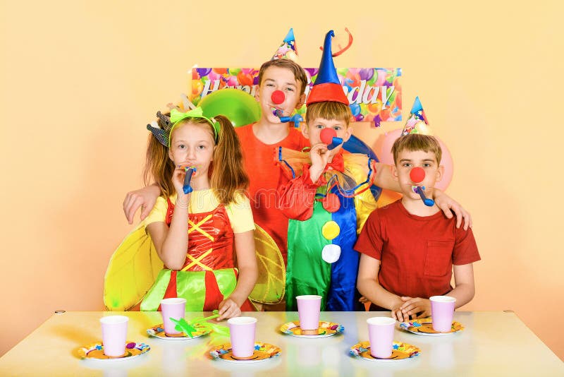 Fyra barn som blåser i tonen för sin clown-födelsedag