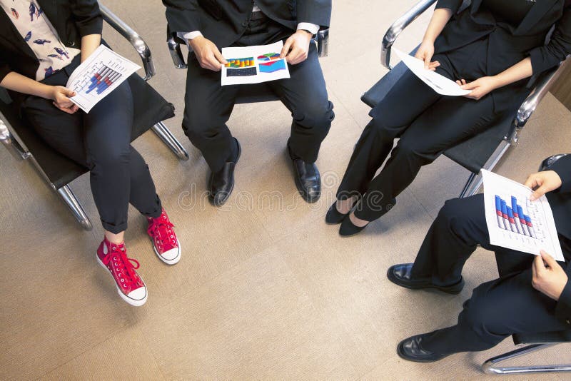 Fyra coworkers som rymmer ett affärsmöte, sikt för hög vinkel royaltyfri bild Fyra coworkers som rymmer ett affärsmöte, sikt för hög vinkel royaltyfri bild
