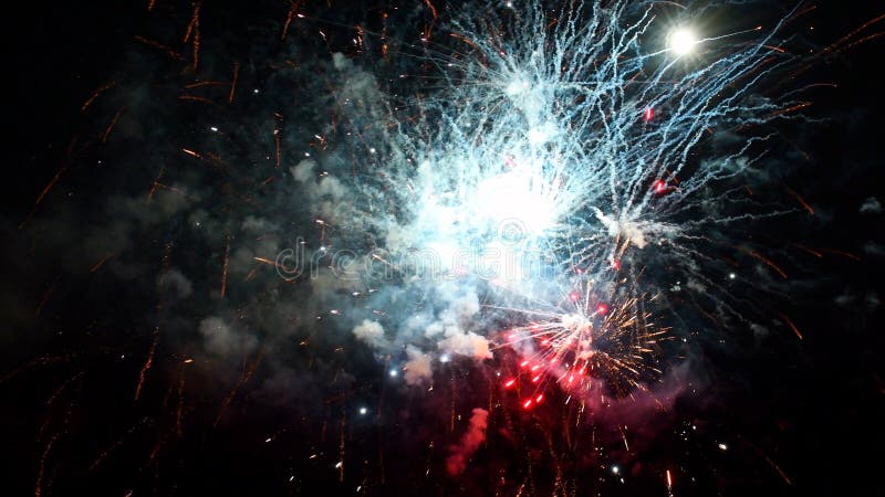 Fyrverkerier som exploderar i olika färger i den mörka natthimlen stock video