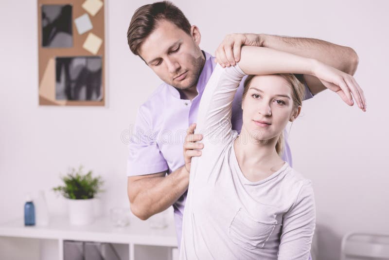 Fysioterapeut och patient som övar med armen under sjukgymnastik royaltyfria bilder Fysioterapeut och patient som övar med armen under sjukgymnastik royaltyfria bilder