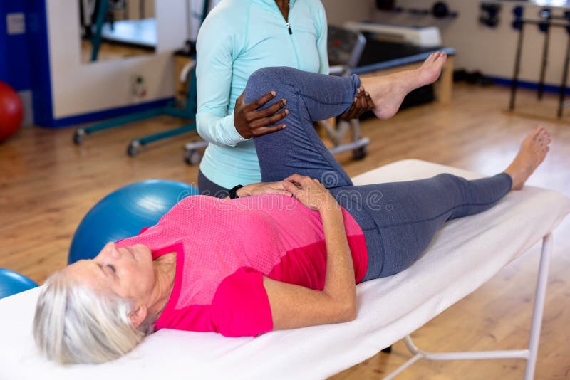 Fysiotherapeut die actief hoger vrouwenbeen in sportencentrum uitrekken stock afbeelding Fysiotherapeut die actief hoger vrouwenbeen in sportencentrum uitrekken stock afbeelding