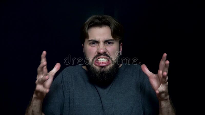 Fâché du jeune homme avec la barbe Jeune homme fâché avec la barbe, montrant ses dents grognant dans la colère Expressions du vis banque de vidéos