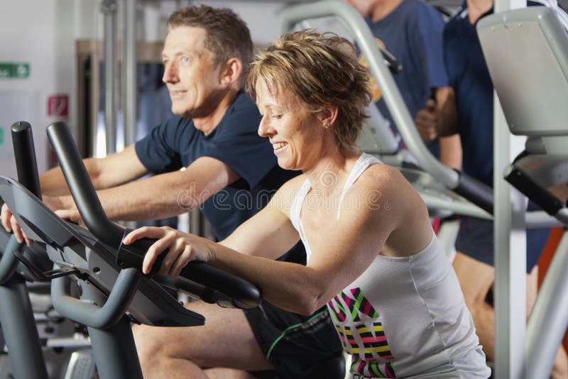 Mature couple working out at fitness centre on excercise bikes. Mature couple working out at fitness centre on excercise bikes