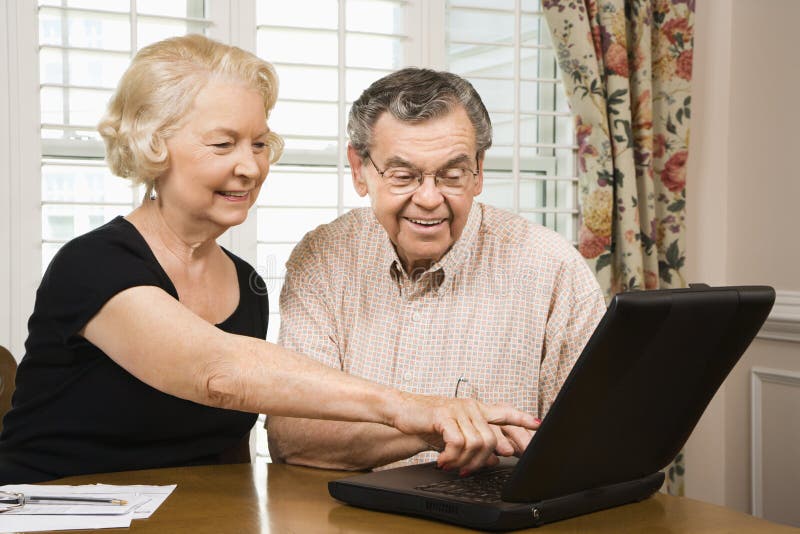 Mature Caucasian couple looking at laptop. Mature Caucasian couple looking at laptop.