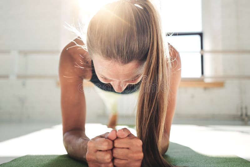 Färdig ung kvinna som gör plankagenomkörare för att förbättra hennes abs Kvinnlig i idrottshallen som gör crossfit royaltyfri fotografi